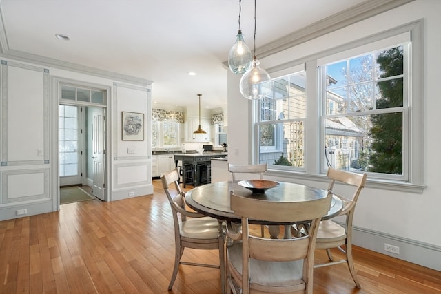 dining space featuring light hardwood / wood-style flooring, ornamental molding, and plenty of natural light