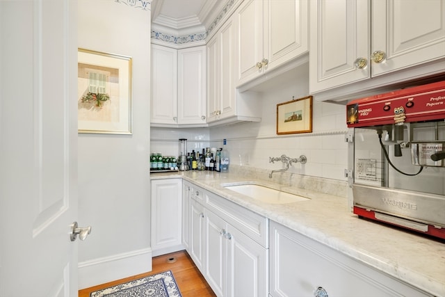 kitchen with white cabinets, light stone counters, tasteful backsplash, and sink