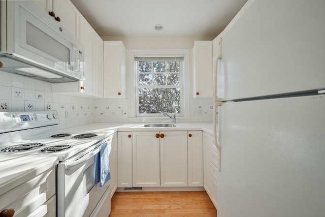 kitchen featuring white appliances, sink, white cabinets, light hardwood / wood-style flooring, and tasteful backsplash