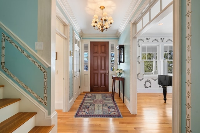 foyer with crown molding, light hardwood / wood-style flooring, and a chandelier