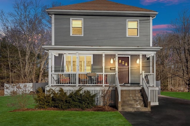 view of property with covered porch and a lawn