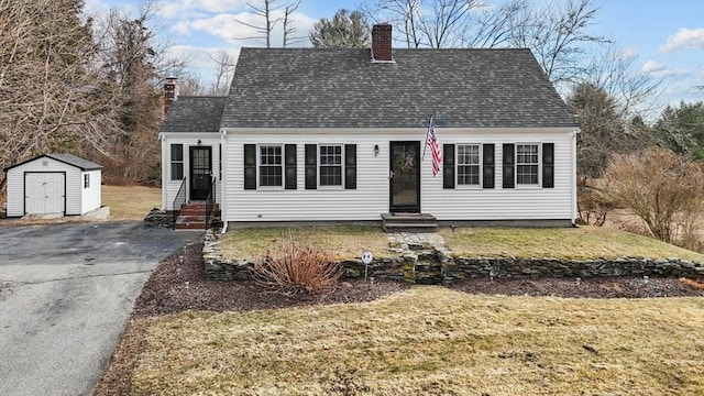 cape cod home featuring a front lawn and a storage unit