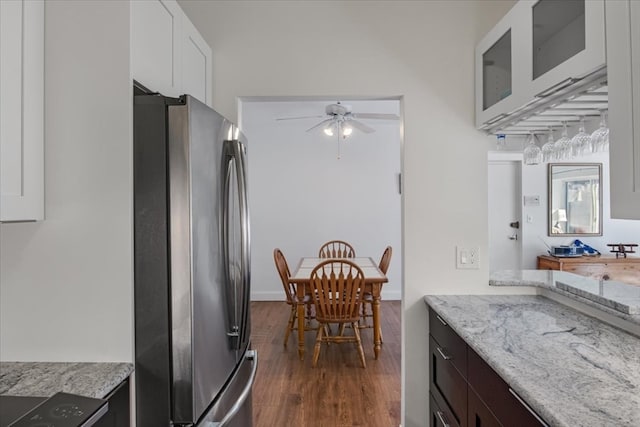 kitchen featuring white cabinetry, ceiling fan, light stone counters, dark hardwood / wood-style flooring, and stainless steel fridge