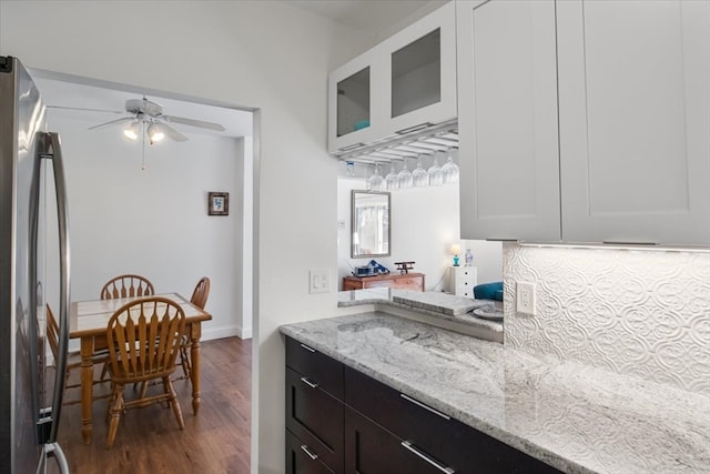 kitchen featuring light stone counters, ceiling fan, white cabinets, dark hardwood / wood-style floors, and stainless steel refrigerator