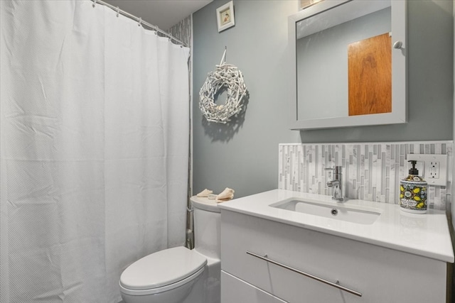 bathroom featuring vanity, toilet, and backsplash