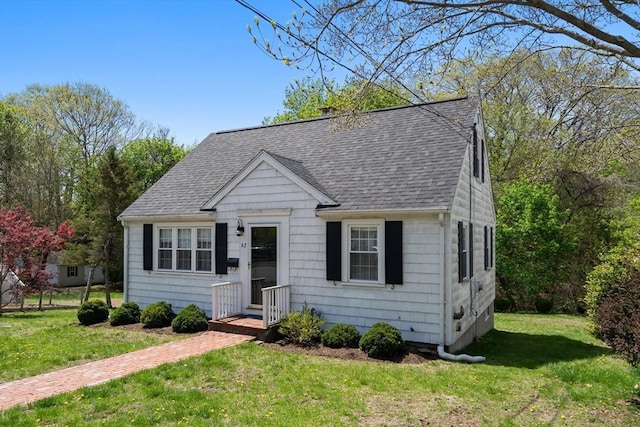 view of front of home with roof with shingles and a front yard