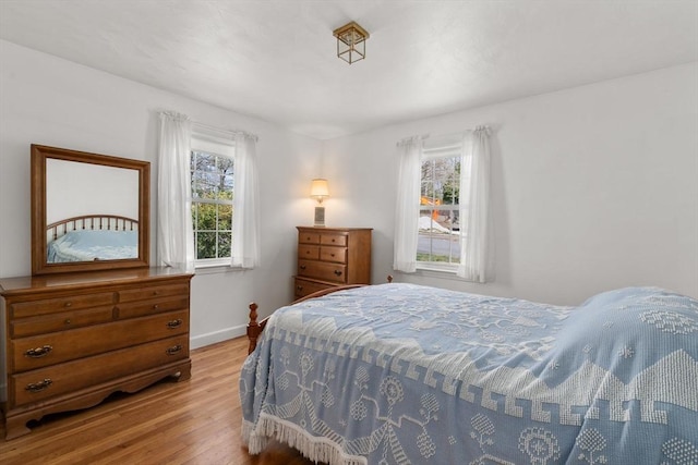 bedroom featuring baseboards, multiple windows, and wood finished floors
