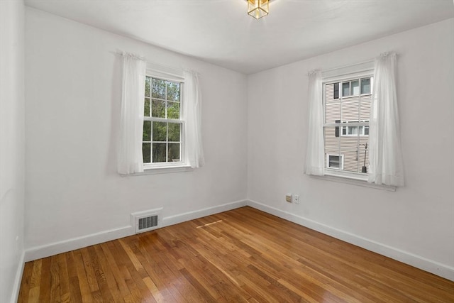 empty room with visible vents, baseboards, and hardwood / wood-style floors