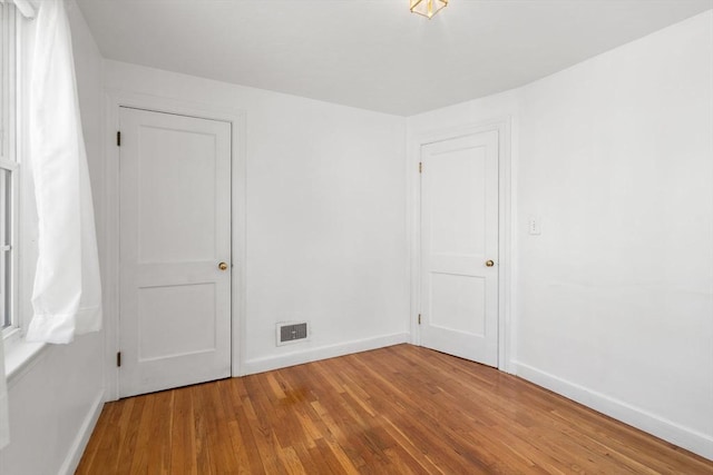 empty room featuring baseboards, visible vents, and wood finished floors