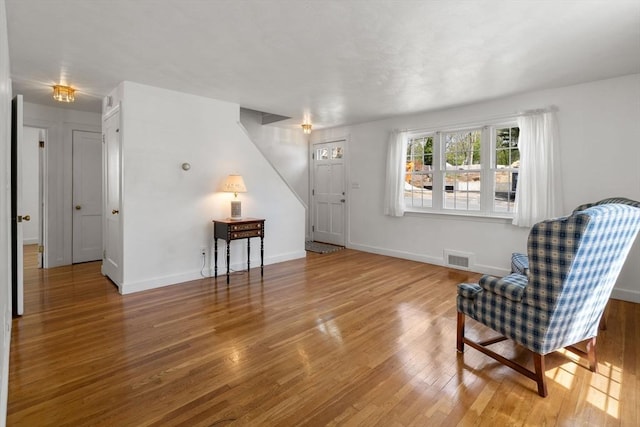 living area featuring visible vents, baseboards, and wood finished floors