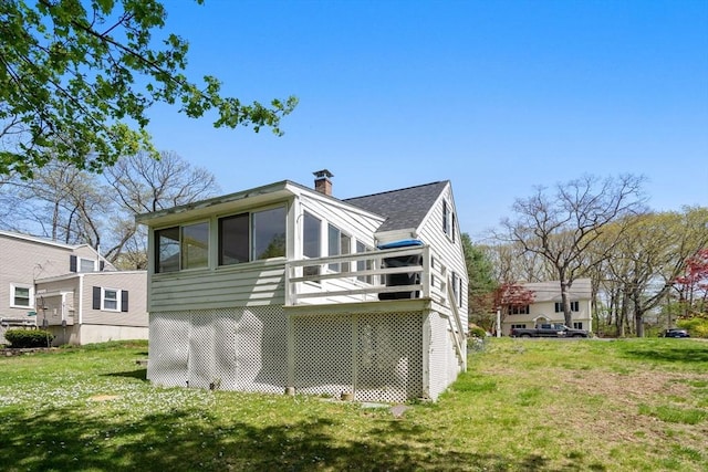 back of house with a lawn, a chimney, and a sunroom