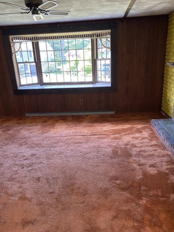 62 Duncan Rd, Stoughton, MA 02072 - carpeted empty room with wood walls and a ceiling fan