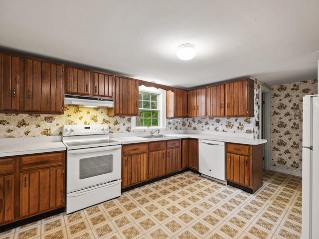 51 Quaboag Rd, Acton, MA 01720 - kitchen with white appliances, under cabinet range hood, wallpapered walls, light countertops, and brown cabinetry