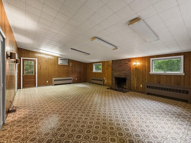 51 Quaboag Rd, Acton, MA 01720 - below grade area with radiator heating unit, a brick fireplace, a wall mounted air conditioner, wood walls, and carpet