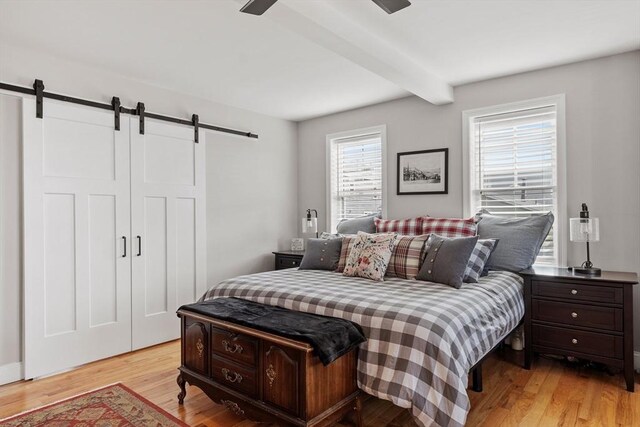 57 Railroad Ave Unit C1, Salisbury, MA 01952 - bedroom with a barn door, beam ceiling, and light wood-style flooring