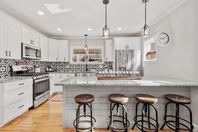 57 Railroad Ave Unit C1, Salisbury, MA 01952 - kitchen featuring stainless steel appliances, ornamental molding, a breakfast bar, white cabinetry, and backsplash