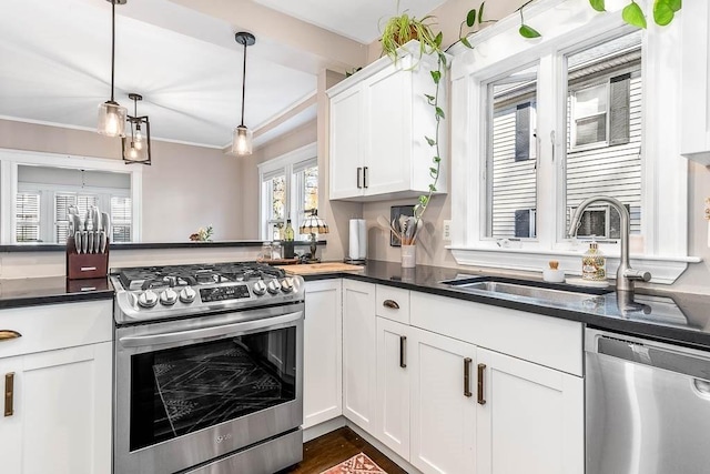 kitchen with pendant lighting, stainless steel appliances, dark countertops, and white cabinets