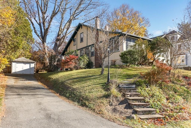 view of property exterior with a yard, a garage, and an outdoor structure