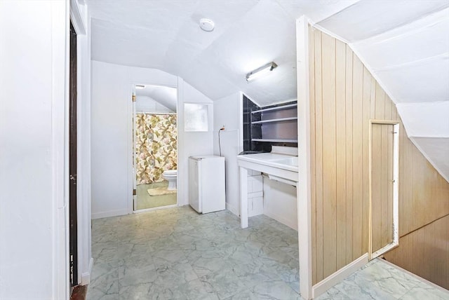 bathroom with vaulted ceiling, wooden walls, and toilet