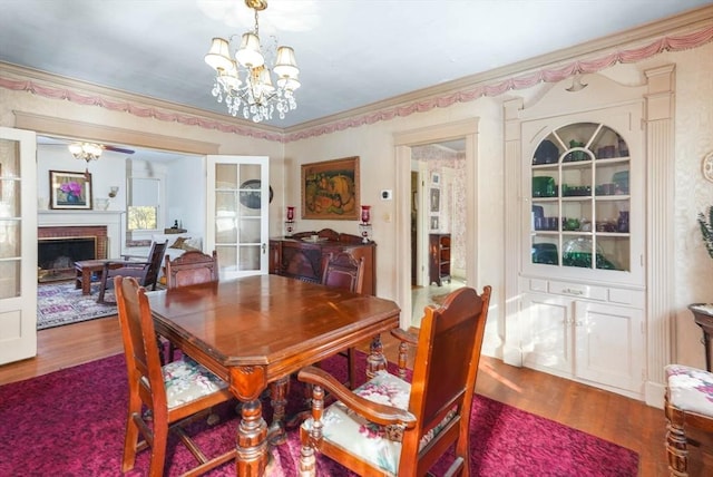 dining room with wood-type flooring, a notable chandelier, and a fireplace