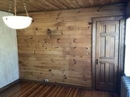 interior space featuring wood ceiling, radiator, wooden walls, and wood finished floors