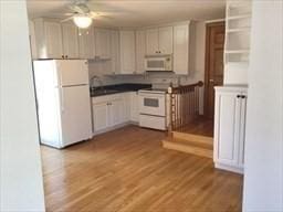 kitchen with light wood-style flooring, white appliances, a sink, white cabinets, and dark countertops