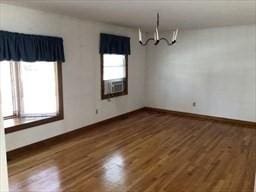 unfurnished dining area with a healthy amount of sunlight, a notable chandelier, and wood finished floors