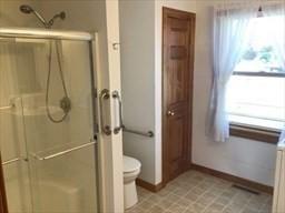 full bath featuring toilet, a shower stall, and baseboards