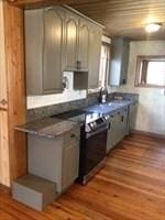 kitchen featuring a sink, range with electric cooktop, dark countertops, and wood finished floors