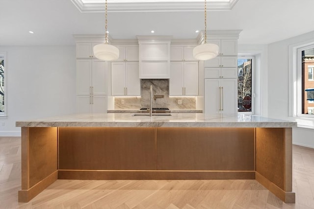 kitchen featuring premium range hood, decorative light fixtures, a large island, light stone counters, and white cabinetry