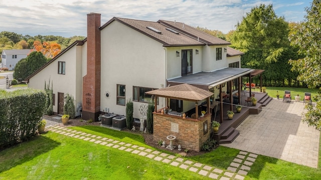 rear view of house featuring central air condition unit, a patio area, and a yard