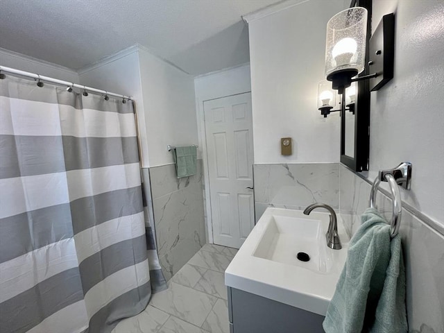 bathroom featuring marble finish floor, wainscoting, a textured ceiling, and vanity