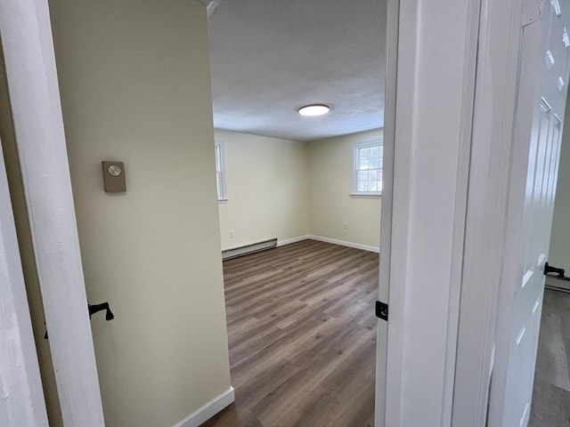 hall with baseboards, a baseboard heating unit, and dark wood-style flooring