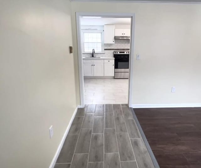 corridor featuring wood tiled floor, a sink, and baseboards