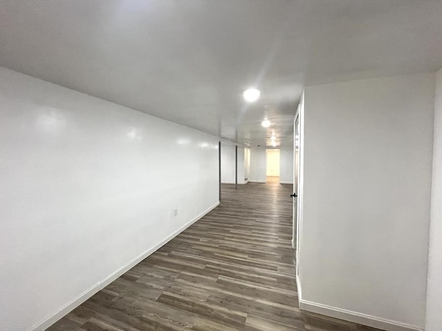 hallway featuring baseboards and dark wood-type flooring