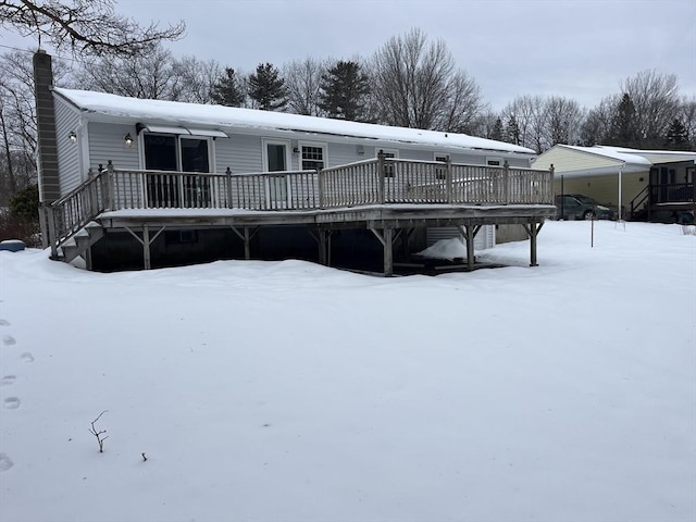 snow covered property featuring a chimney and a wooden deck