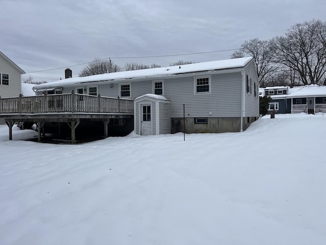 snow covered back of property with a deck