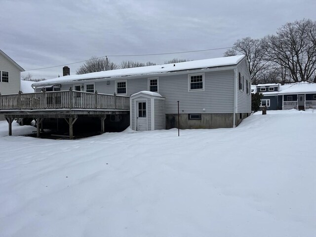 snow covered rear of property with a wooden deck