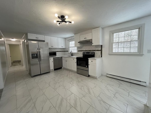 kitchen featuring a baseboard radiator, marble finish floor, stainless steel appliances, under cabinet range hood, and a sink