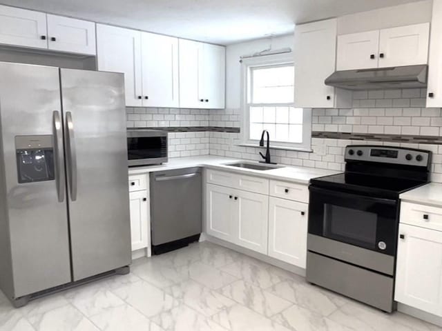 kitchen featuring under cabinet range hood, appliances with stainless steel finishes, marble finish floor, and a sink