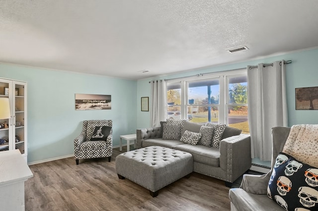 living room featuring hardwood / wood-style flooring, ornamental molding, a textured ceiling, and baseboard heating