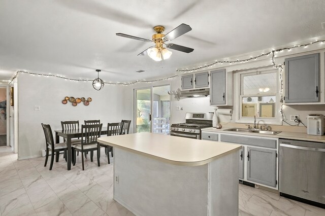 kitchen featuring gray cabinets, ceiling fan, a center island, and stainless steel appliances