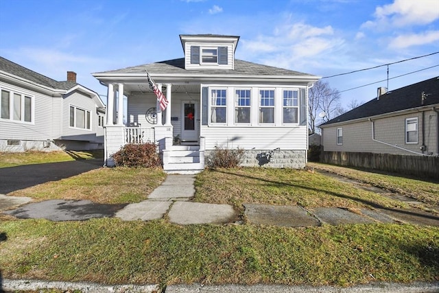 bungalow with covered porch and a front lawn