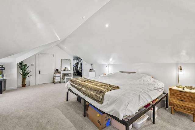 bedroom with light colored carpet, a spacious closet, and lofted ceiling