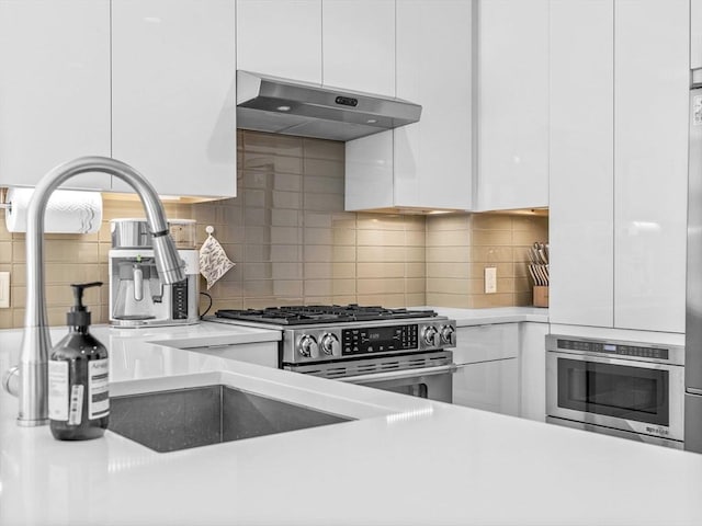 kitchen with light countertops, decorative backsplash, white cabinetry, modern cabinets, and under cabinet range hood