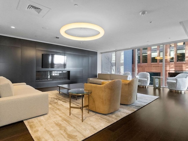 living area with floor to ceiling windows, visible vents, and wood finished floors