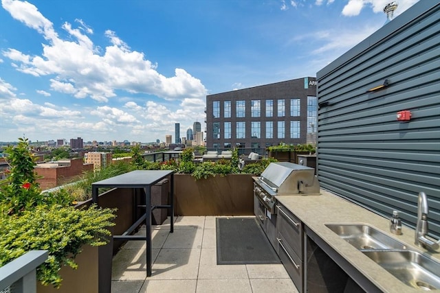 view of patio / terrace with a view of city, an outdoor kitchen, a sink, and a grill