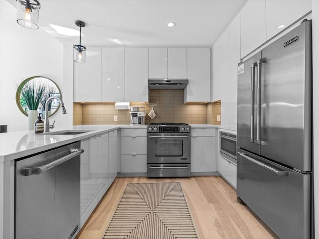 kitchen featuring pendant lighting, stainless steel appliances, light countertops, white cabinets, and modern cabinets