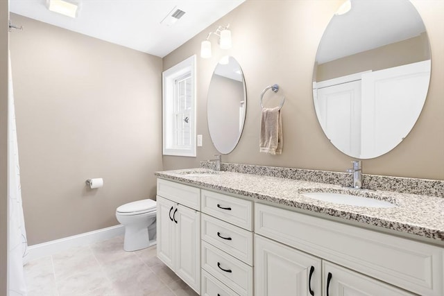 bathroom with baseboards, a sink, double vanity, and toilet