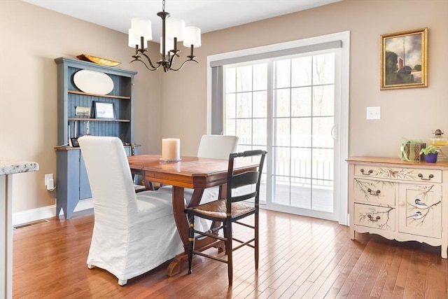 dining space featuring an inviting chandelier, plenty of natural light, and wood finished floors